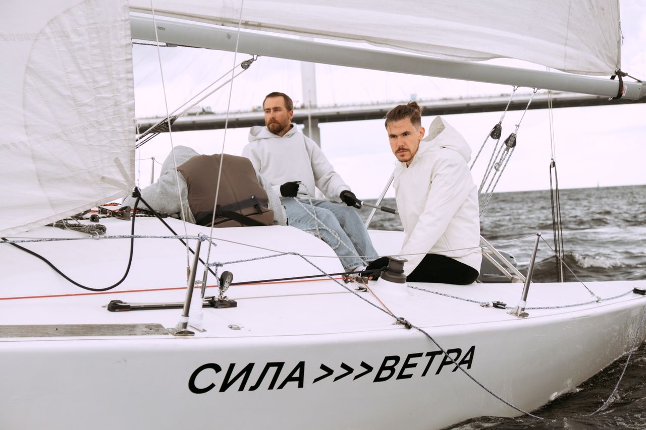 Two men sailing a yacht on a breezy day, showcasing teamwork and adventure.